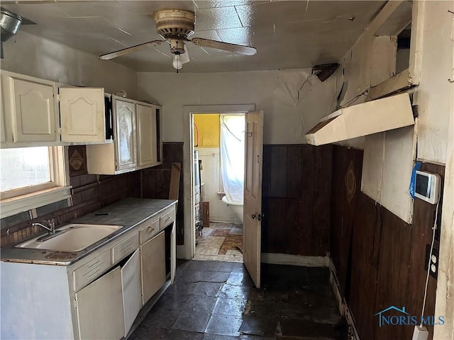 1331 Grand Ave, Toledo, OH 43606 - kitchen featuring a ceiling fan, wainscoting, a sink, wooden walls, and white cabinets