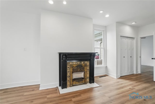details featuring a fireplace with flush hearth, wood finished floors, baseboards, and recessed lighting