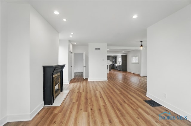 unfurnished living room with recessed lighting, visible vents, and light wood-type flooring