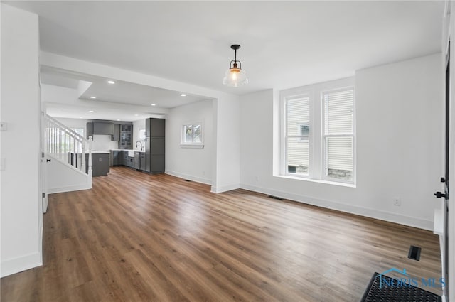 unfurnished living room featuring baseboards, dark wood-style flooring, and visible vents