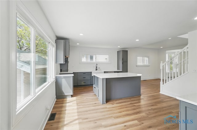 kitchen featuring light countertops, plenty of natural light, a center island, and gray cabinetry