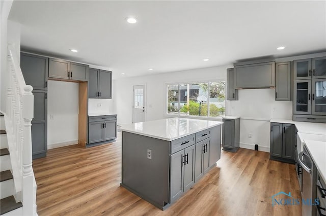 kitchen with recessed lighting, light wood-style flooring, glass insert cabinets, and gray cabinetry