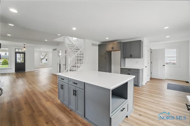 kitchen with gray cabinets, recessed lighting, a center island, and light wood-style flooring
