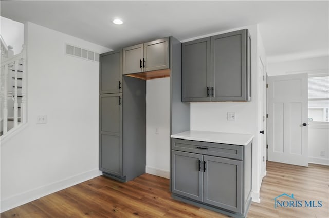 kitchen featuring visible vents, wood finished floors, and gray cabinetry