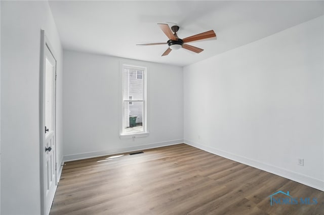 empty room with baseboards, a ceiling fan, and wood finished floors