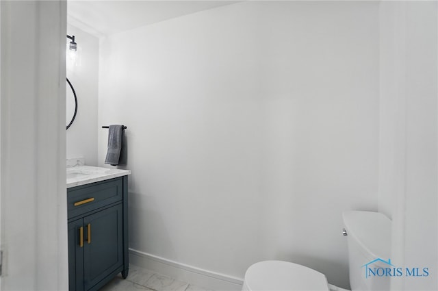 half bathroom with baseboards, marble finish floor, vanity, and toilet