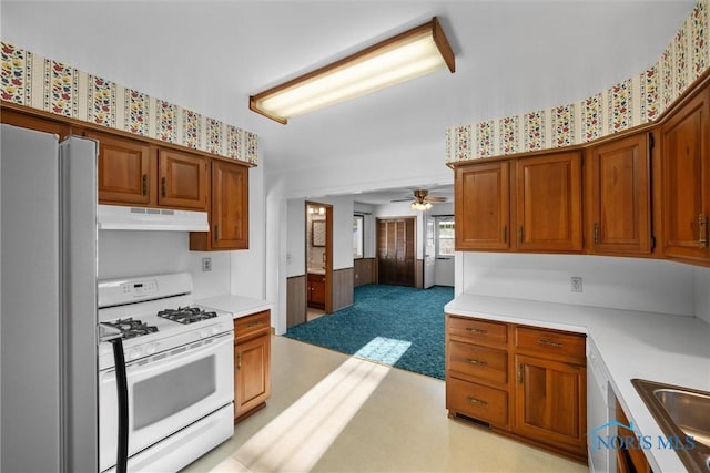 5148 Fern Dr, Toledo, OH 43613 - kitchen featuring freestanding refrigerator, gas range gas stove, light countertops, under cabinet range hood, and brown cabinets