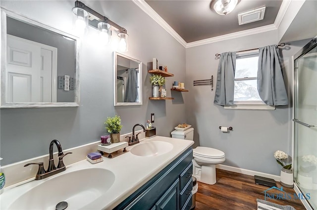 full bathroom featuring a stall shower, toilet, crown molding, and a sink