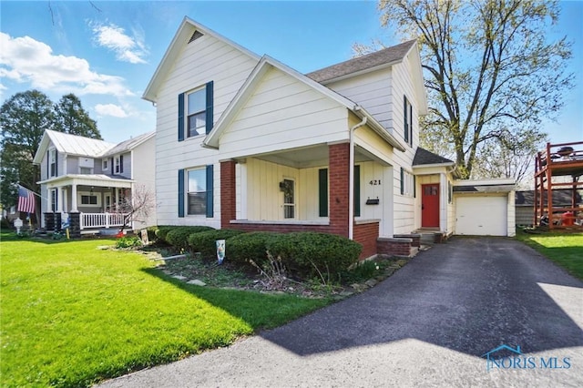 view of front of house featuring a front lawn, driveway, a porch, board and batten siding, and an outdoor structure
