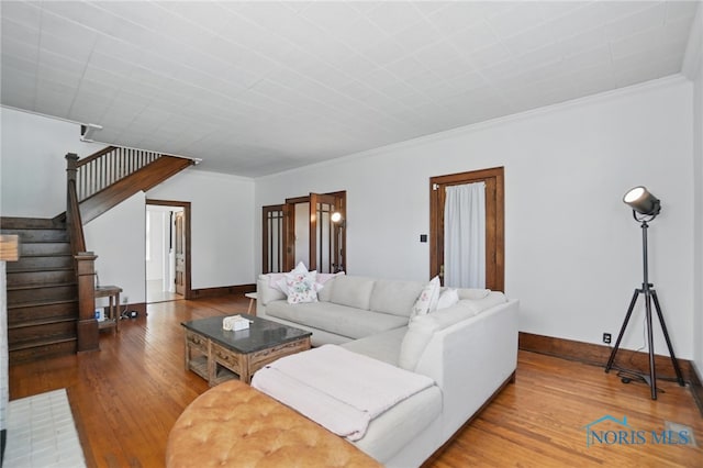living area with hardwood / wood-style flooring, stairs, crown molding, and baseboards