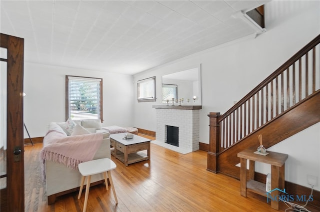 living room featuring baseboards, wood finished floors, a fireplace, and stairs