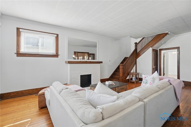 living area with a fireplace, wood finished floors, stairs, and baseboards