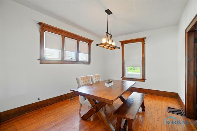 dining area featuring baseboards, hardwood / wood-style floors, and visible vents