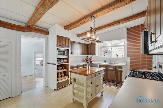 kitchen featuring a center island, a sink, hanging light fixtures, stainless steel appliances, and beam ceiling