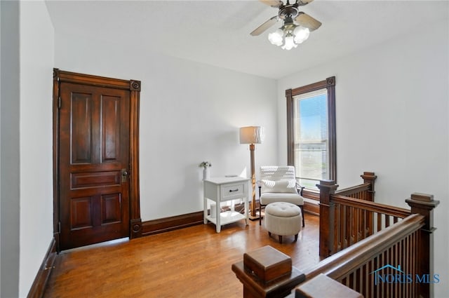 interior space featuring ceiling fan, baseboards, wood finished floors, and a crib