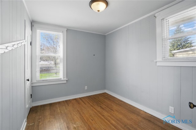 unfurnished room featuring baseboards, wood finished floors, and crown molding