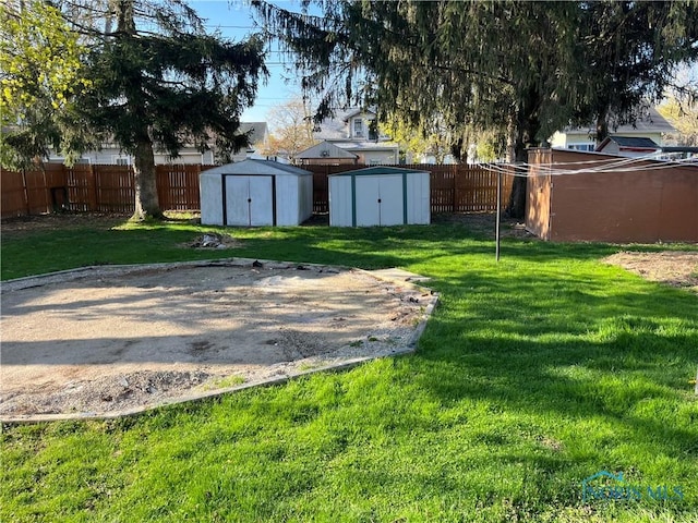 view of yard featuring fence, a storage unit, and an outbuilding