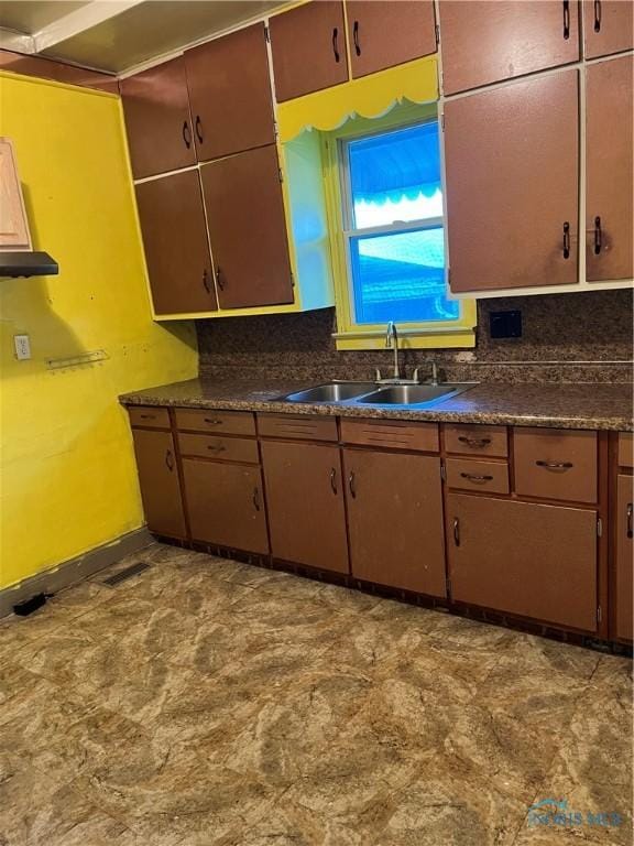 kitchen with decorative backsplash, dark countertops, and a sink