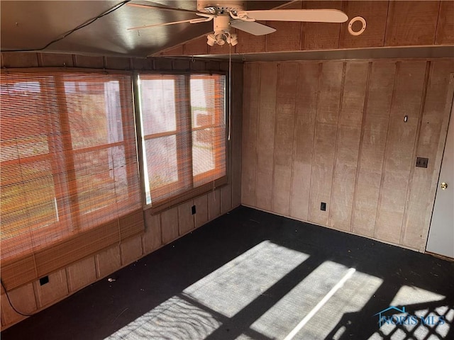 spare room with wood walls and ceiling fan