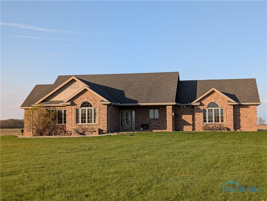 ranch-style home with a shingled roof, brick siding, and a front yard
