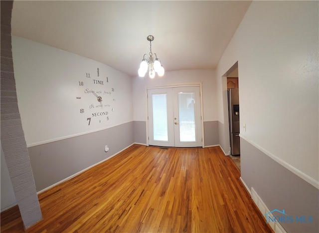 interior space with visible vents, light wood finished floors, a notable chandelier, and french doors