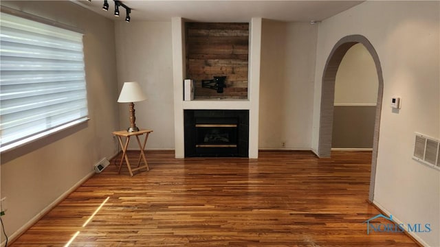 living area with a fireplace, wood finished floors, visible vents, and baseboards