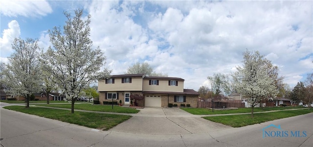 view of front facade with fence, an attached garage, a front lawn, and driveway