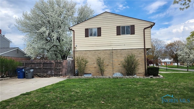 view of home's exterior featuring fence, a lawn, and brick siding