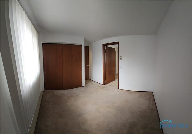unfurnished bedroom with light carpet and a closet
