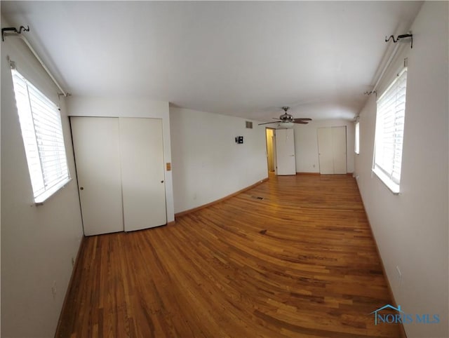 empty room with plenty of natural light, a ceiling fan, and wood finished floors