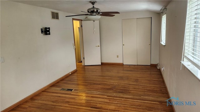 unfurnished bedroom featuring baseboards, wood finished floors, visible vents, and a closet