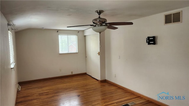 empty room with baseboards, a ceiling fan, wood finished floors, and visible vents
