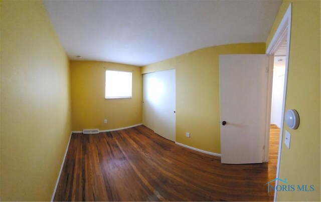spare room featuring baseboards, wood finished floors, and visible vents