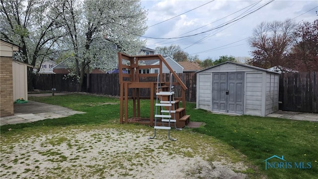 view of jungle gym featuring a storage unit, a lawn, an outbuilding, and a fenced backyard
