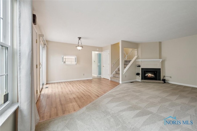 5718 Aspen Dr Unit 15, Toledo, OH 43615 - unfurnished living room with a lit fireplace, light colored carpet, stairway, baseboards, and light wood finished floors