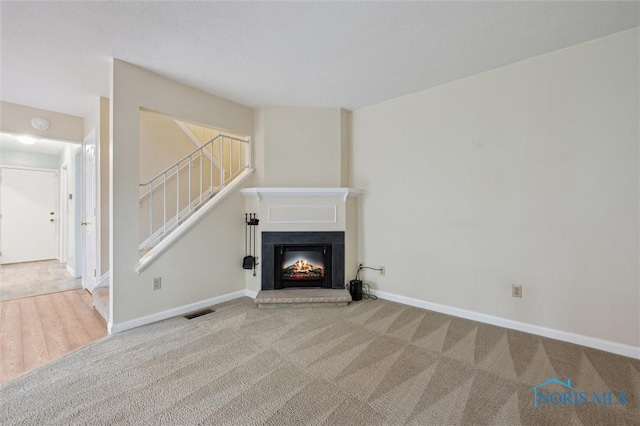 5718 Aspen Dr Unit 15, Toledo, OH 43615 - unfurnished living room featuring visible vents, stairway, carpet floors, baseboards, and a warm lit fireplace