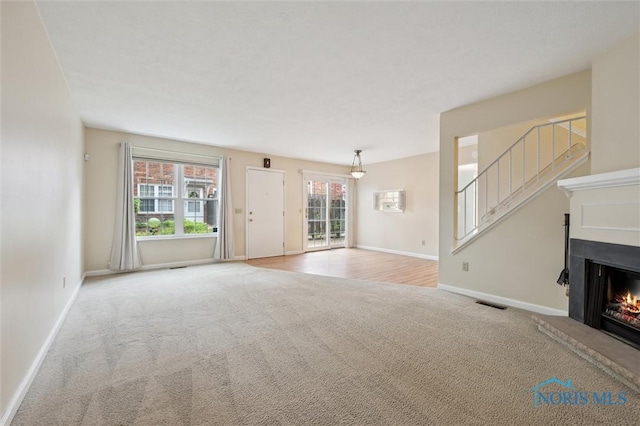 5718 Aspen Dr Unit 15, Toledo, OH 43615 - unfurnished living room with carpet flooring, a warm lit fireplace, visible vents, and baseboards