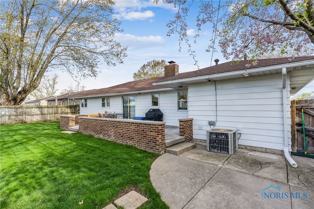 back of house featuring a fenced backyard, central AC unit, a yard, and a patio