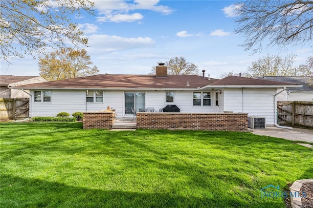 back of property with a chimney, fence, central AC, a patio area, and a lawn