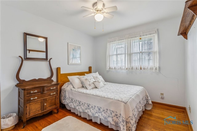 bedroom with ceiling fan, baseboards, and wood finished floors
