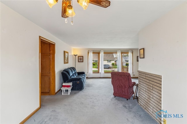 living area featuring baseboards, a ceiling fan, and carpet flooring