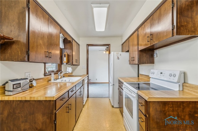 kitchen with light floors, light countertops, white appliances, and a sink