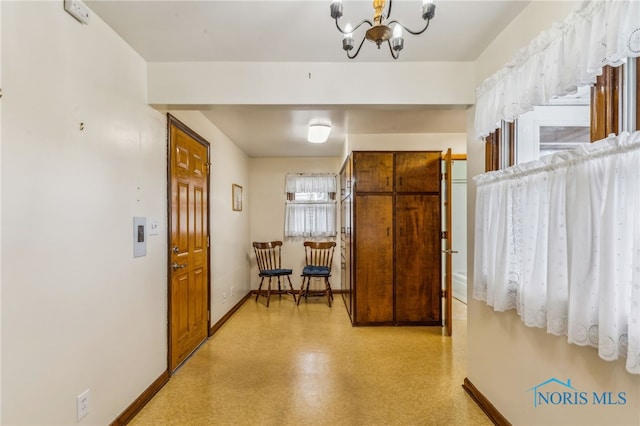 hallway with an inviting chandelier and baseboards