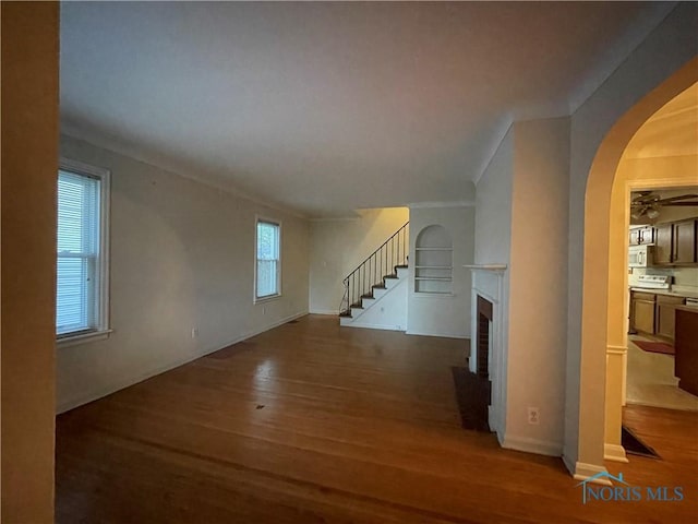 3721 Kershaw Ave, Toledo, OH 43613 - unfurnished living room with wood finished floors, stairway, a fireplace, arched walkways, and a ceiling fan