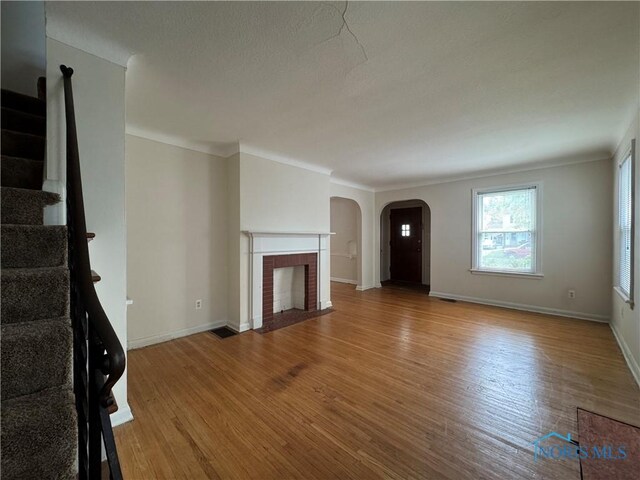 3721 Kershaw Ave, Toledo, OH 43613 - unfurnished living room featuring stairway, wood finished floors, arched walkways, baseboards, and ornamental molding