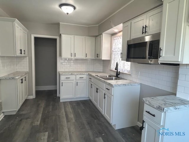 419 Spencer St, Toledo, OH 43609 - kitchen with white cabinets, dark wood finished floors, a sink, stainless steel microwave, and tasteful backsplash
