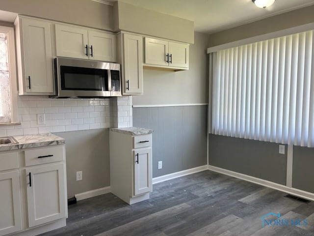 419 Spencer St, Toledo, OH 43609 - kitchen featuring stainless steel microwave, tasteful backsplash, light countertops, dark wood finished floors, and white cabinetry
