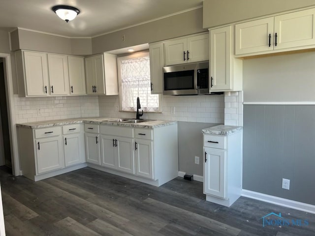 419 Spencer St, Toledo, OH 43609 - kitchen with stainless steel microwave, decorative backsplash, white cabinetry, and a sink