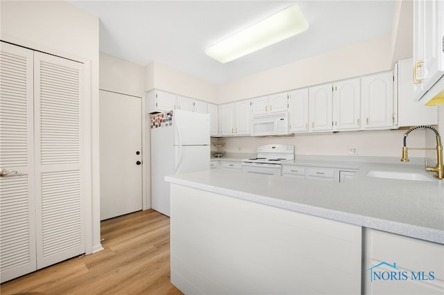 kitchen with white appliances, white cabinets, light wood finished floors, a sink, and a peninsula