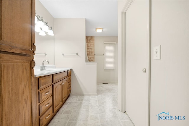 full bathroom with stone finish floor, vanity, and baseboards